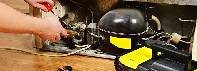 Refrigerator repair technician fixing the compressor and wiring in Cramerton, NC