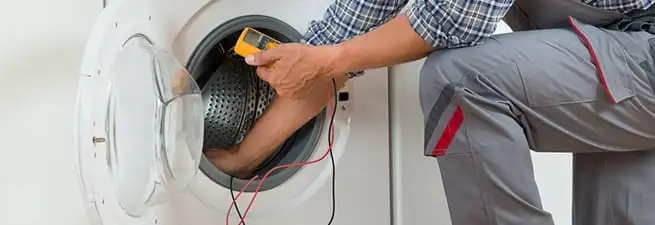 Dryer repair technician inspecting and repairing a clothes dryer in Charlotte, NC
