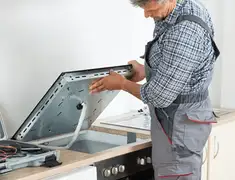 Appliance repair technician installing a built-in cooktop in Charlotte, NC