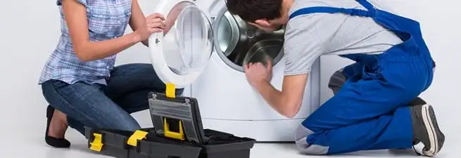 Washer repair technician inspecting a front-load washing machine with tools in Charlotte, NC