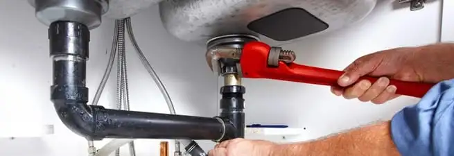 Garbage disposal repair technician tightening the sink drain and disposal connection in Charlotte, NC
