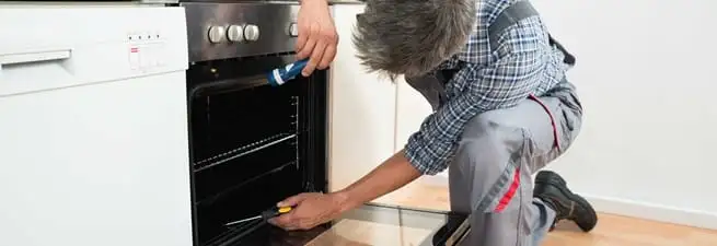 Oven repair technician inspecting and servicing an electric oven in Charlotte, NC