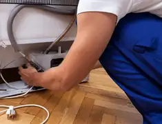Appliance repair technician fixing refrigerator water line and connections in Charlotte, NC