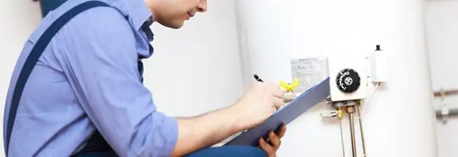 Water heater repair technician inspecting the unit and recording service notes in Charlotte, NC