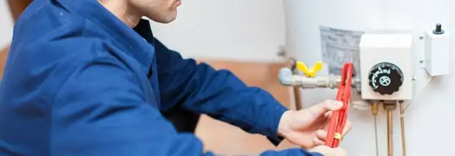 Water heater repair technician adjusting the temperature control and gas valve in Charlotte, NC